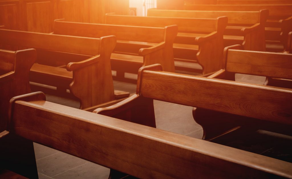 Empty church pews in warm light, illustrating what happens to church property when a church closes