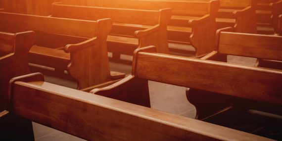 Empty church pews in warm light, illustrating what happens to church property when a church closes