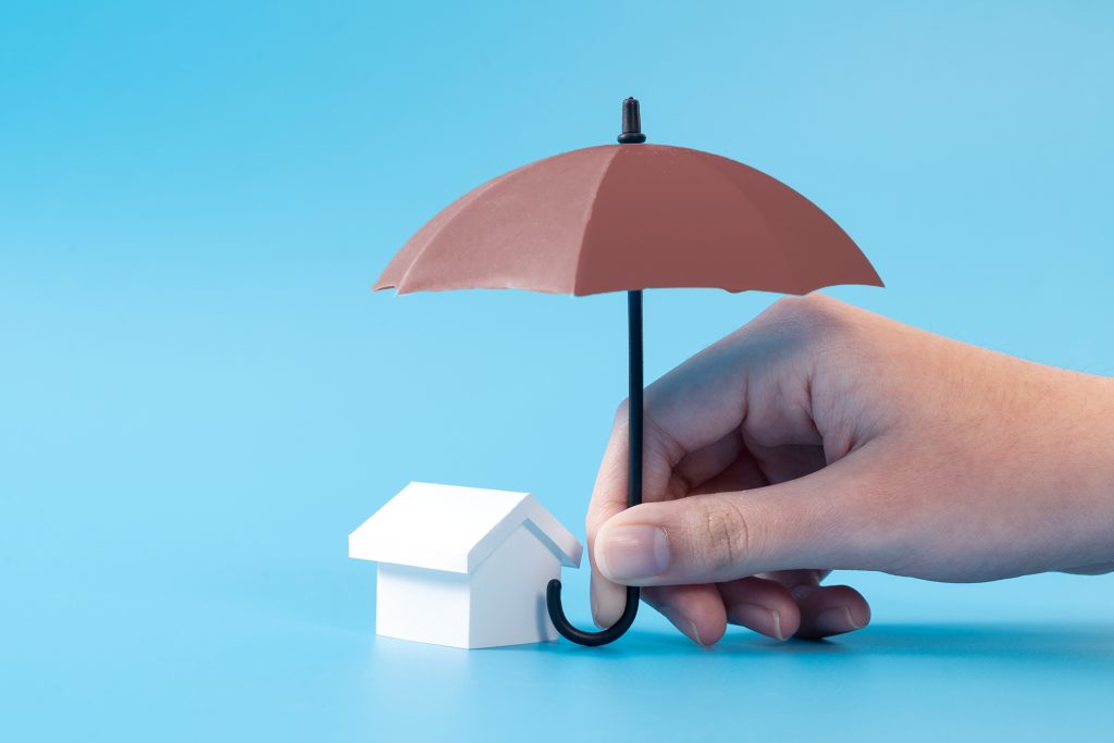 General liability insurance — umbrella held over a small house, representing property protection
