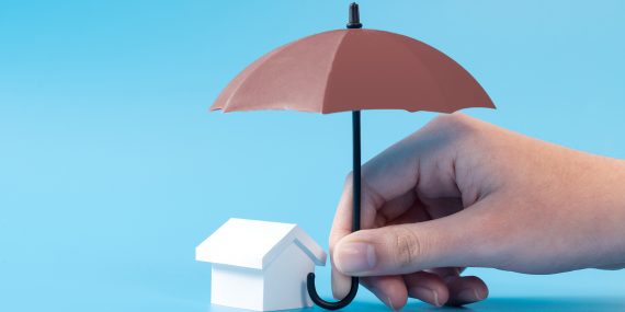 General liability insurance — umbrella held over a small house, representing property protection